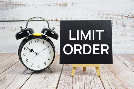 Limit Order text with easel and alarm clock on wooden background