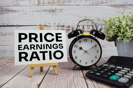Price Earnings Ratio text with alarm clock and calculator on wooden backgroundの写真素材