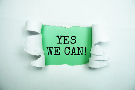 Yes We Can! message written on green paper with torn paper backgroundの写真素材