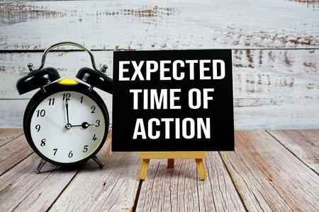 Expected Time Of Action text with easel and alarm clock on wooden backgroundの写真素材