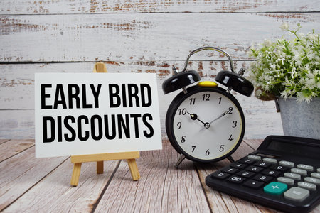 Early Bird Discounts text with alarm clock and calculator on wooden backgroundの写真素材
