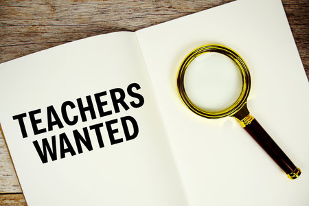 Teachers Wanted text message written on paper note with magnifying glass top view on wooden backgroundの写真素材