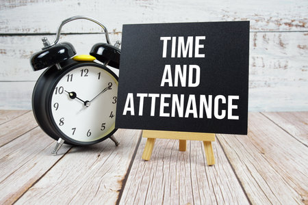Time and Attendance text with easel and alarm clock on wooden backgroundの写真素材