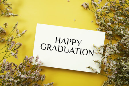 Happy Graduation text with flowers decoration on yellow backgroundの写真素材