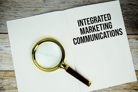 Integrated Marketing Communications text written on paper with magnifying glass on wooden background