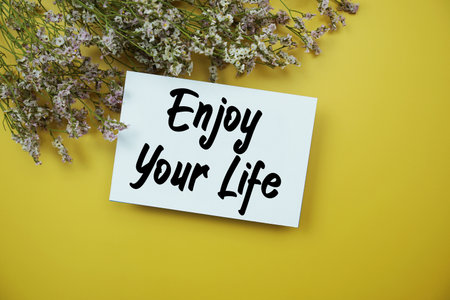 Enjoy Your Life text with flowers decoration on yellow backgroundの写真素材