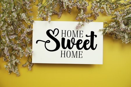 Home Sweet Home text with flowers decoration on yellow backgroundの写真素材