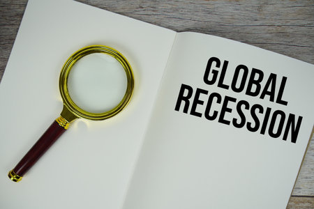 Global Recession text written on chalkboard with alarm clock on wooden backgroundの写真素材