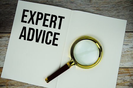 Expert Advice text message written on paper note with magnifying glass top view on wooden backgroundの写真素材