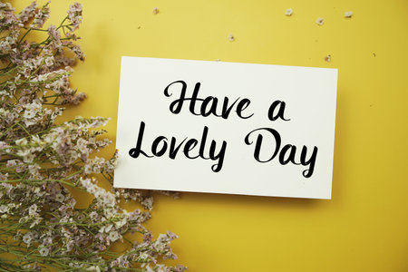 Have a Lovely Day text with flowers decoration on yellow backgroundの写真素材