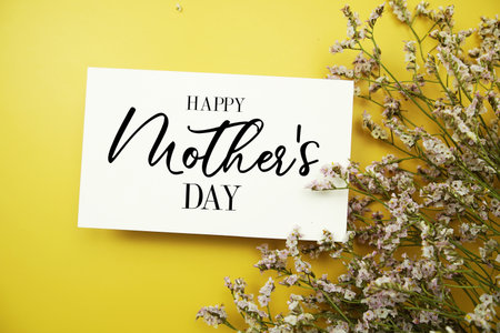 Happy Mother's Day text with flowers decoration on yellow backgroundの写真素材