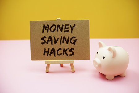 Money Saving Hacks text with white piggy bank on pink and yellow backgroundの写真素材