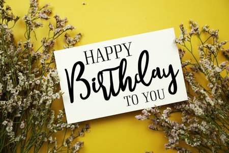 Happy Birthday to you text with flowers decoration on yellow backgroundの写真素材