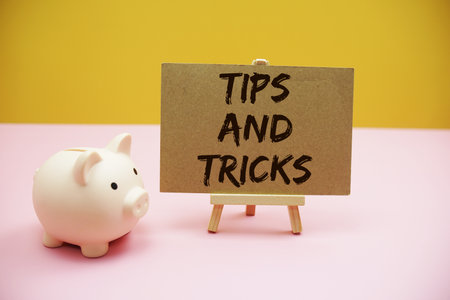 Tips And Tricks text with white piggy bank on pink and yellow backgroundの写真素材
