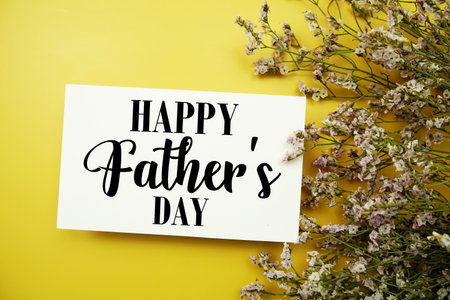 Happy Father's Day text with flowers decoration on yellow backgroundの写真素材
