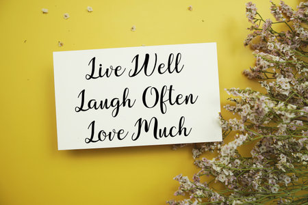 Live wel Laugh often Love much text with flowers decoration on yellow backgroundの写真素材