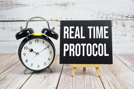 Real Time Protocol text with easel and alarm clock on wooden backgroundの写真素材