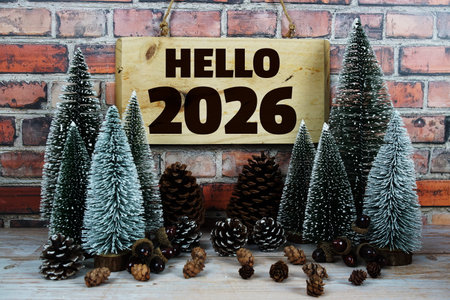 Happy New Year 2026 with Christmas tree and pine cone decoration on old brick wall and wooden backgroundの写真素材