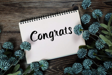Congrats text with flowers decoration on wooden background