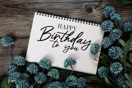 Happy Birthday to you text with flowers decoration on wooden backgroundの写真素材