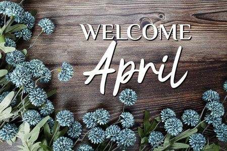 Welcome April text with flowers decoration on wooden background