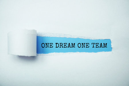 One Dream One Team message written on blue paper with torn paper backgroundの写真素材