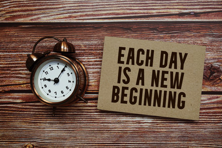 Each day is a new beginning text with alarm clock on wooden backgroundの写真素材