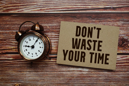Don't Waste Your Time text with alarm clock on wooden background