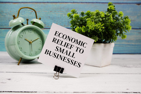 Economic Relief To Small Businesses text written on paper card with alarm clock on wooden background