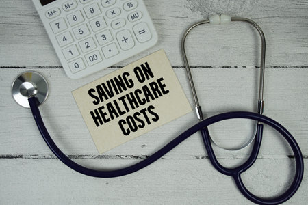 Saving on Healthcare Costs text with Stethoscope and calculator on wooden backgroundの写真素材