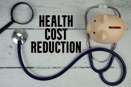 Health Cost Reduction text with Stethoscope and magnifying glass on wooden background