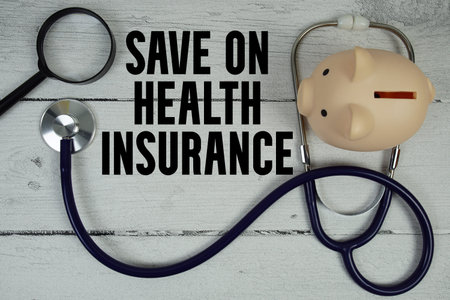 Save on Health Insurance text with Stethoscope and magnifying glass on wooden backgroundの写真素材