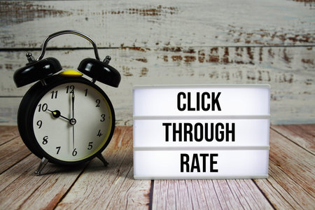 Click Through Rate text on light box with alarm clock on wooden background