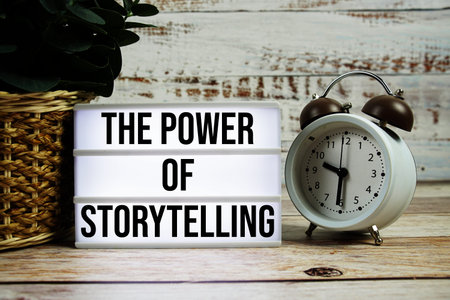 The Power Of Storytelling text on light box with alarm clock on wooden background