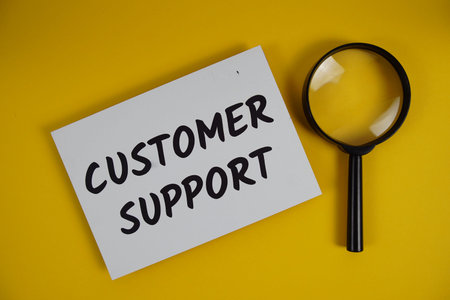 Customer Support letters with magnifying glass flat lay on yellow background