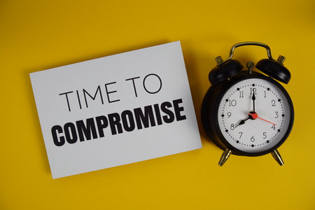 Time to Compromise alphabet letters with alarm clock flat lay on yellow backgroundの写真素材
