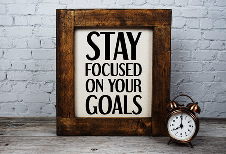 Stay Focused On Your Goals  text with alarm clock  on wooden background