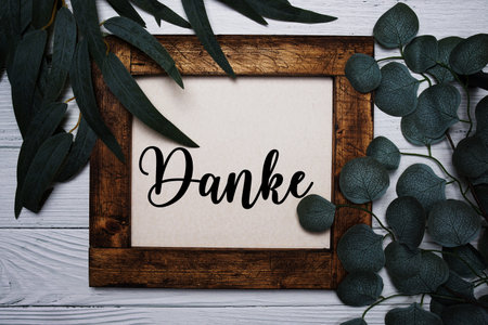 Danke (German thank you) text with artificla green leaf decoratio on wooden backgroundの写真素材