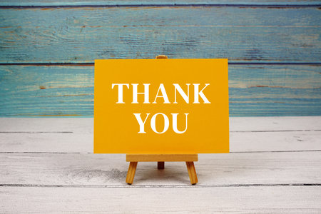 Thank You text written on paper card on wooden background
