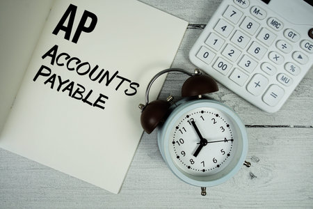 AP Advance Payment text on paper notebook page with alarm clock and calculator on wooden background