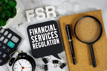 FSR Financial Services Regulation text with Calculator, alarm clock and magnifying glass on marble...