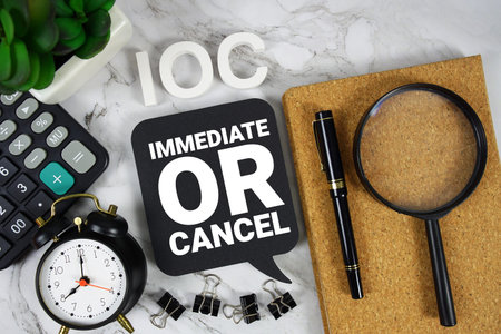 IOC Immediate Or Cancel text with Calculator, alarm clock and magnifying glass on marble background