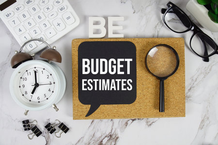 BE - Budget Estimates acronym with alarm clock and magnifying glass, Financial concept backgroundの写真素材