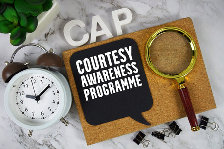 CAP Courtesy Awareness Programme text with alarm clock and magnifying glass on marble background
