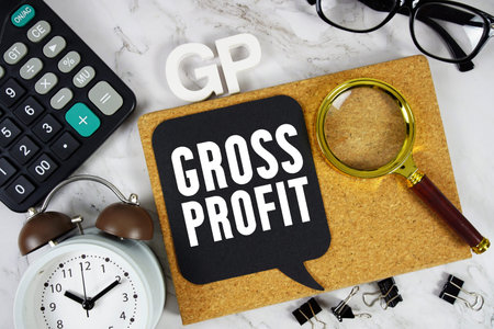 GP Gross Profit text with Calculator, alarm clock and magnifying glass on marble background
