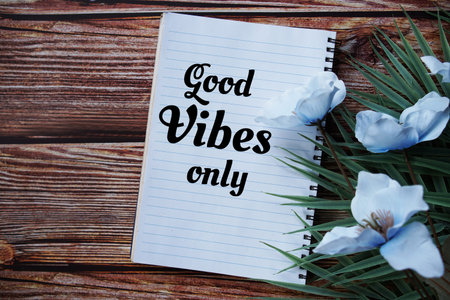 Good vibes only text message with flower and green leaf decoration on wooden backgorund