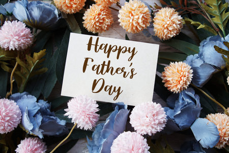 Happy Father's Day text with flowers bouquet decoration on wooen background