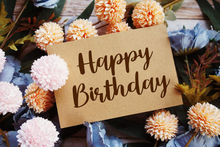 Happy Birthday text with flowers bouquet decoration on wooen background