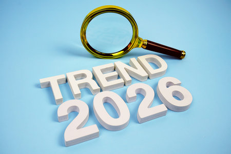 Trend 2026 word with magnifying glass top view on blue background