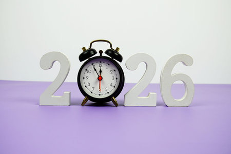 Happy new year 2026 and alarm clock on purple background